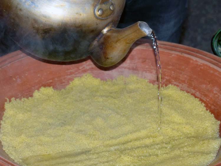 A teakettle of hot water being poured on the couscous.